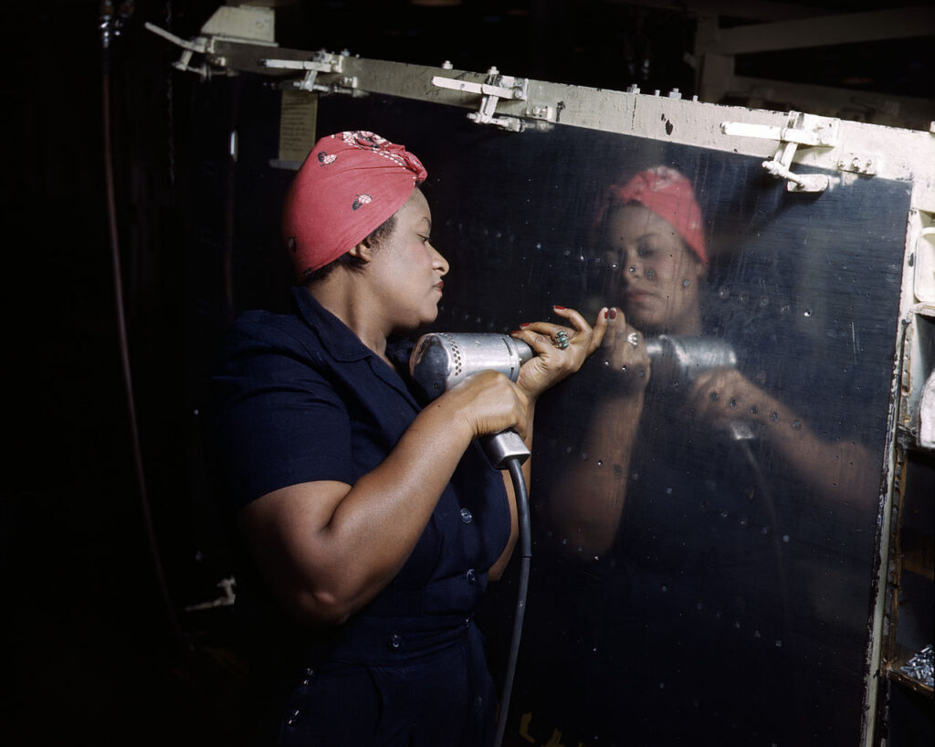 A real-life "Rosie the Riveter" operating a hand drill at Vultee-Nashville, Tennessee, working on an A-31 Vengeance dive bomber.