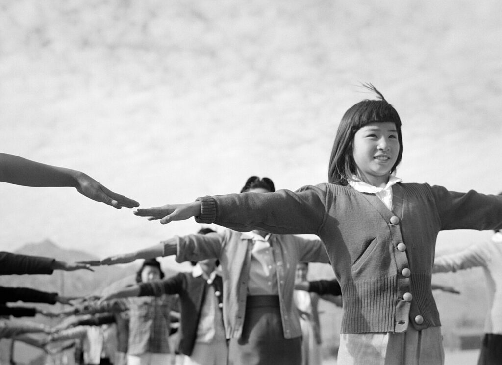 Female internees practicing calisthenics at Manzanar War Relocation Center, Owens Valley, California. In 1943, Ansel Adams followed an invitation by newly appointed camp director R